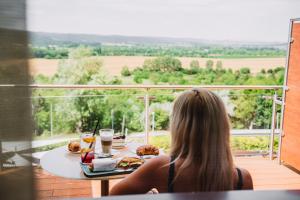 een vrouw aan een tafel met een bord eten bij Wabi Hotel - Beauty & Dental Center in Sopron