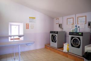 een wasruimte met 2 wasmachines en een raam bij Camping Le Saint Clair in Moustiers-Sainte-Marie