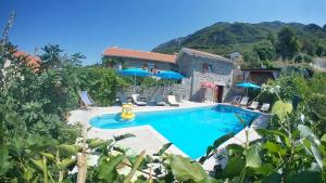 una piscina con sombrillas frente a una casa en Mediteraneo Villa en Kaluđerovići