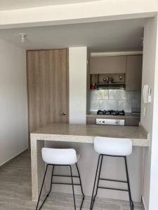 a kitchen with two white stools at a counter at Apartamento en Ricaurte conjunto Puerto Azul Club House in Ricaurte