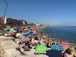 a crowd of people sitting on a beach with umbrellas at Maison Chene petit appartement in Bisceglie