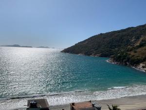 ein Gewässer mit Strand und Berg in der Unterkunft AP ESPETACULAR VISTA MAR PRAINHA EM ARRAIAL DO CABO in Arraial do Cabo