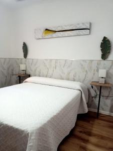 a bedroom with a white bed and two tables at Ángeles home in El Vendrell