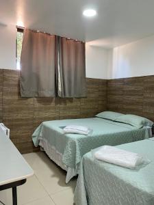 1 dormitorio con 2 camas y ventana en Cabanos Suites, en Maragogi