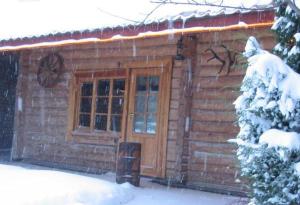 a log cabin with a door in the snow at Brīvdienu māja Mētriņi in Ķekava