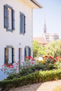 un edificio blanco con ventanas azules y flores en Maison Gamboia, chambres et table d'hôtes au calme avec jardin, en Hasparren