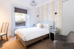 a bedroom with a bed and a chair and a window at Sunbank House Metro Hotel in Perth