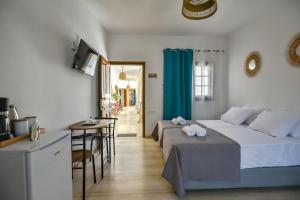 a bedroom with two beds and a table and a kitchen at Eva Studios & Apartments in Agia Pelagia
