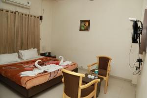 a hotel room with a bed and a table and chairs at HOTEL SAI PASO in Shirdi