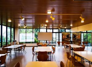 a dining room with tables and chairs and a screen at ISOLA Izukogen in Ito