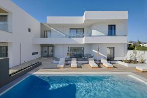 a villa with a swimming pool in front of a house at Mare Suites in Lékhaion