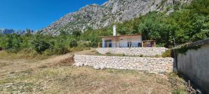 a house with a stone wall in front of a mountain at Home of Laurel in Kotor