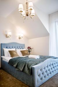 Una cama azul en un dormitorio con una lámpara de araña en Złota Nuta Villa en Mikołajki