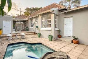 a swimming pool in front of a house at Hampton Collection - Trendy 2 Sleeper Apartment with Pool in Durban