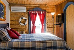 a bedroom with a bed with red curtains and a window at La Galouine Auberge in Tadoussac