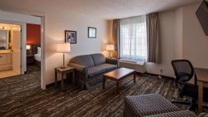 シャールボイにあるCharlevoix Inn & Suites SureStay Collection by Best Westernのソファと椅子付きのホテルルーム