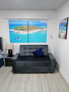 un sofá de cuero negro en una sala de estar con una pintura en Hostal Raatid Manchy, en San Andrés