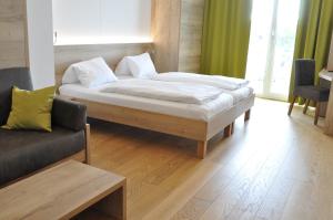 a bedroom with a large bed and a couch at Seehotel Herlinde in Podersdorf am See