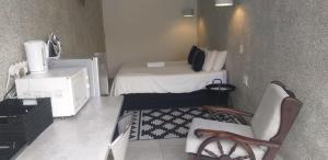 a small room with a bed and a desk and chairs at The Guesthouse Klerksdorp in Klerksdorp