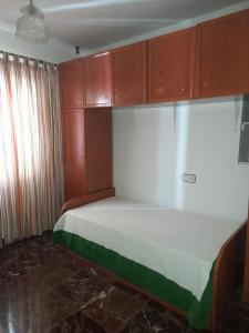 Habitación pequeña con cama y armarios de madera. en Piso en Montillana, en Montillana