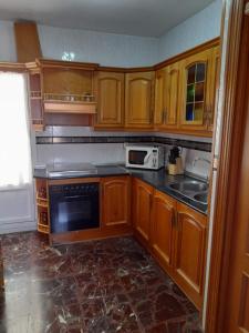 Una cocina con armarios de madera, fregadero y microondas. en Piso en Montillana, en Montillana 2 fotos más