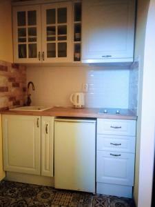 una cocina con armarios blancos y fregadero en Ivanka Guest House, en Obzor
