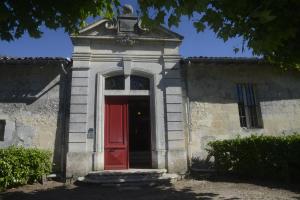 un edificio antiguo con una puerta roja delante en Château Rosemont - Grande maison familiale campagne dans le Médoc avec piscine et tennis à 15 mn Bordeaux en Labarde