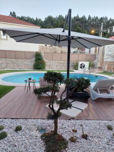 Luxury Vila with Spa and Pool في فيلا دو كوندي: فناء فيه مظلة وكراسي ومسبح