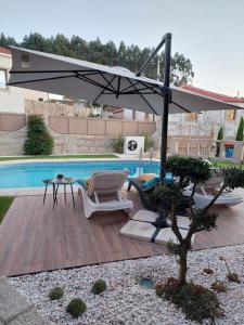 um pátio com um guarda-sol e cadeiras e uma piscina em Luxury Vila with Spa and Pool em Vila do Conde
