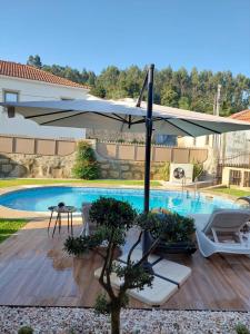 a patio with an umbrella and a swimming pool at Luxury Vila with Spa and Pool in Vila do Conde