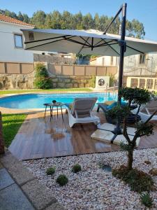 a patio with an umbrella and a chair and a pool at Luxury Vila with Spa and Pool in Vila do Conde