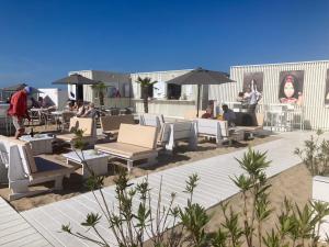 eine Terrasse mit Liegestühlen und Sonnenschirmen am Strand in der Unterkunft Micheline's plekje in Ostende