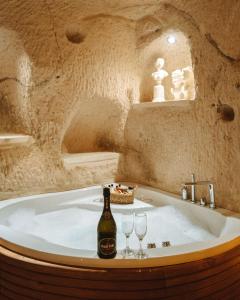 a bath tub with a bottle of champagne and two wine glasses at Juno Cappadocia Adults Only in Uçhisar