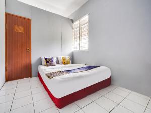 a bed in a white room with a window at SPOT ON 91393 Budiluhur 10 Homestay in Bandung