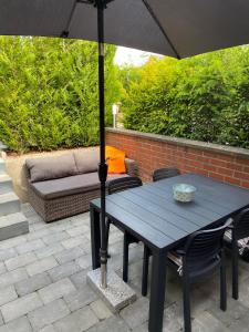 - une table en bois avec un parasol sur la terrasse dans l'établissement bij Petros, à Opglabbeek