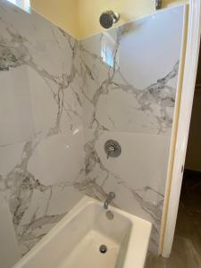 La salle de bains est pourvue d'une baignoire blanche et d'un mur en marbre. dans l'établissement Beachway Inn, à Arroyo Grande