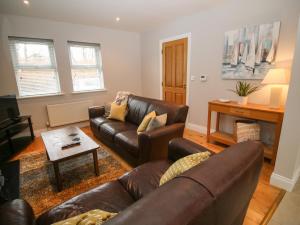 uma sala de estar com um sofá de couro e uma mesa em Pebble Lodge em Kenmare