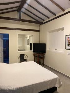 a bedroom with a bed and a flat screen tv at Suite Praia da Feiticeira in Ilhabela