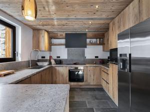 a kitchen with wooden cabinets and a stainless steel refrigerator at Chalet Val-d'Isère, 7 pièces, 14 personnes - FR-1-567-38 in Val-d'Isère