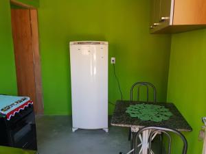 un frigorifero bianco in una stanza verde con un tavolo di Chale 8A a Cunha