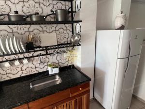 a kitchen with a white refrigerator and a black counter top at Residencial Solariun Ilhabela in Ilhabela