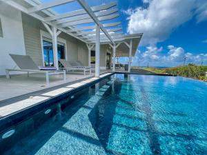 a swimming pool in front of a house at JADE - Villa Créole de Standing et de charme ,vue mer , proche des plages & piscine privée haut de gamme in Saint-François