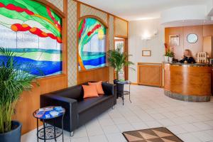 a lobby with a couch and a woman at a bar at Hotel Gilda in Laigueglia