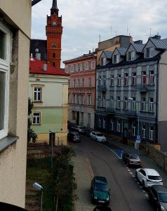 una ciudad con coches aparcados en una calle con una torre de reloj en Old Town Plus, en Tarnów