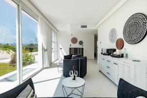 a living room with white walls and large windows at Cara a Bentu - Charming Rooms in Tortolì