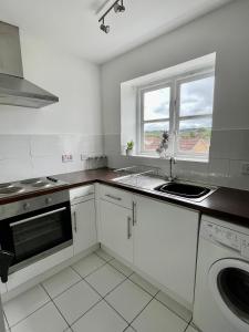 a white kitchen with a sink and a window at Modern 2 bedroom apartment near Glasgow Airport in Paisley