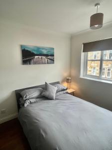 a bedroom with a bed with a painting on the wall at Modern 2 bedroom apartment near Glasgow Airport in Paisley