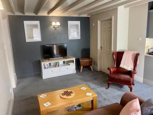 a living room with a couch and a tv and a table at Heart of the village Cotswold Cottage in Crudwell. in Crudwell