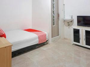 a bedroom with a bed and a sink and a television at OYO 91375 Pondok Feby Makassar in Makassar