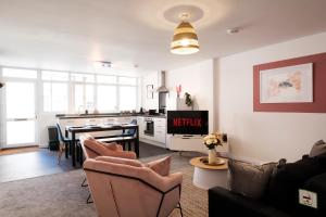 a living room with a couch and a kitchen at Glevum Lodge - 2 Bedroom Town Centre Apartment in Cirencester